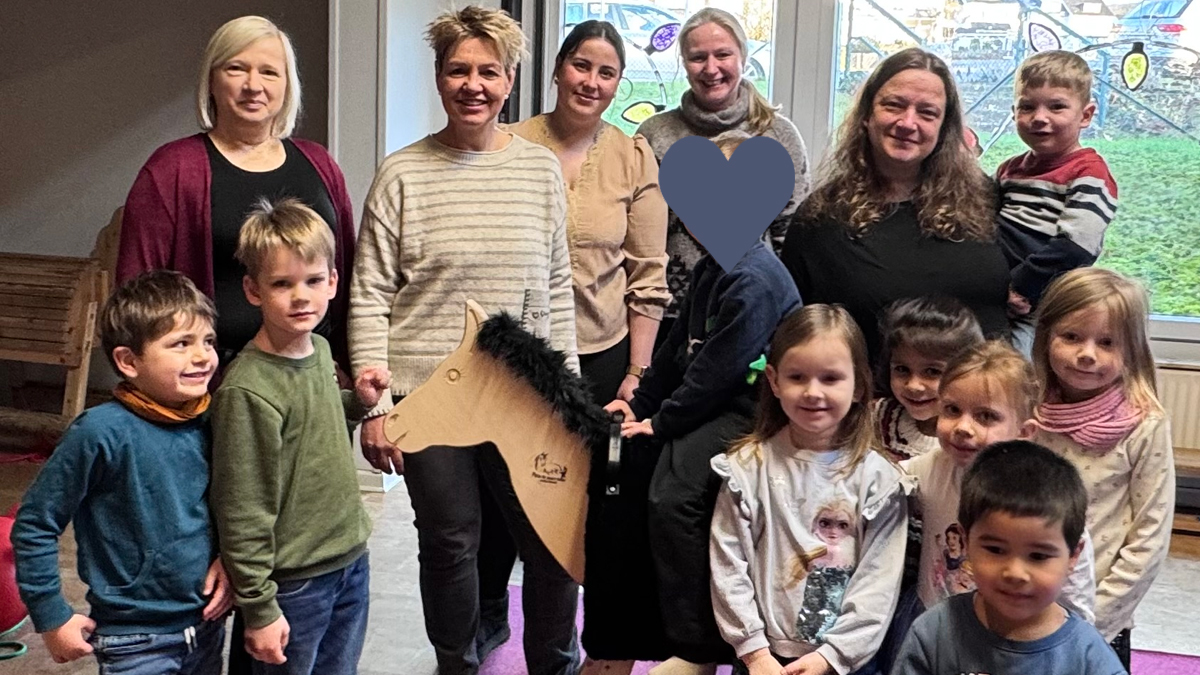 Brigitte Friedrichs, Antje Koch und Anja Matzk (hintere Reihe 4. von links, 2. von links und links) vom Club Soroptimist Einbeck-Northeim übergeben ein Holzpferd an die Kinder des Regenbogenkindergarten. Die Leiterin des Kindergartens Susan Steiner (hintere Reihe rechts) und Erzieherin Michelle Goebel (3. von links) sind sich sicher, dass das neue Pferd Emma von den 100 Kindern freudig aufgenommen wird. 